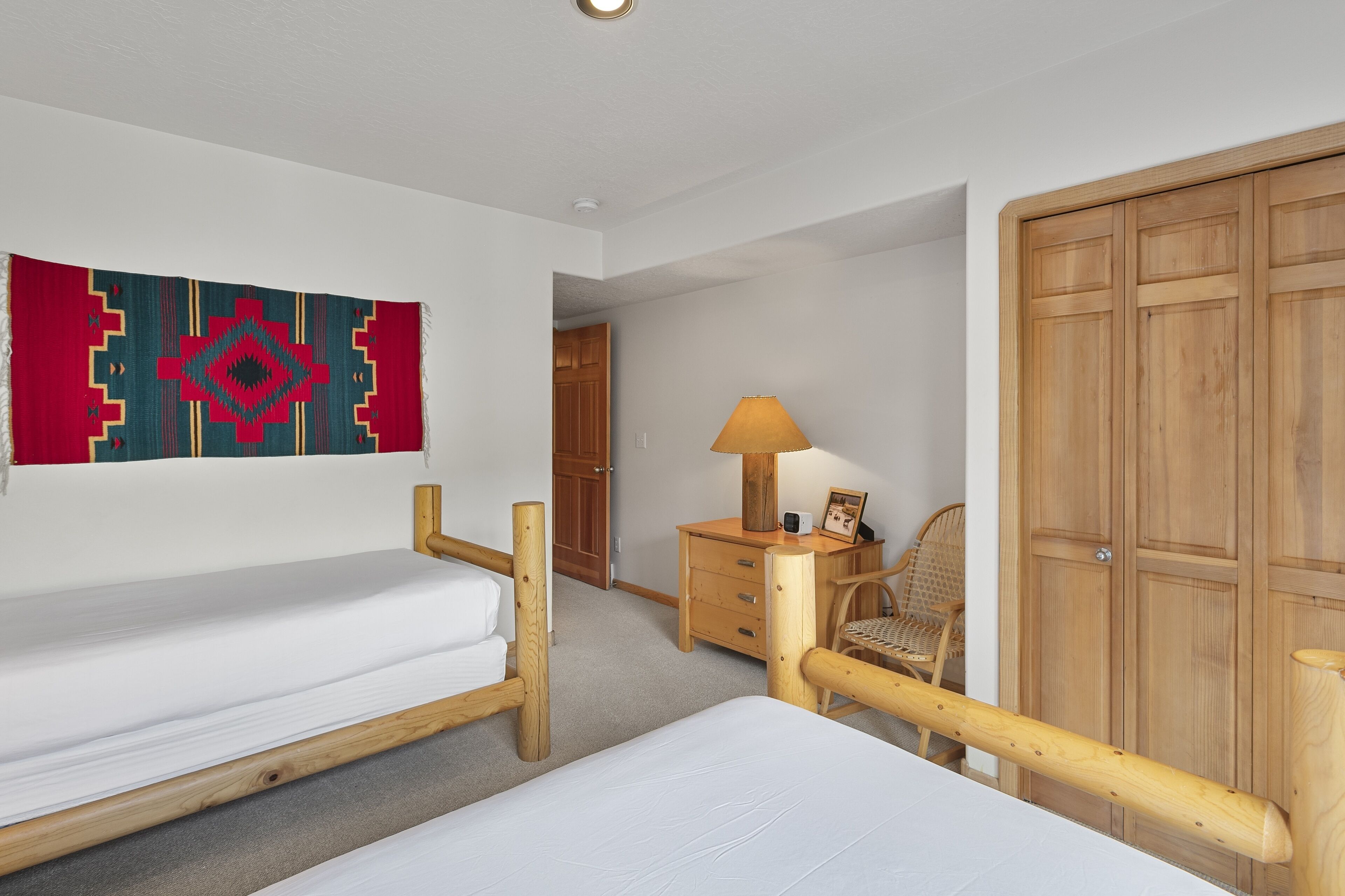 Une chambre à coucher avec un lit en bois, une table de chevet, une chaise, une armoire et une décoration murale.
