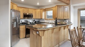 A modern kitchen with wooden cabinets, stainless steel appliances, a granite countertop, and a built-in island. - Boulder Creek at Deer Valley Resort - Three Bedroom Condo with Hot Tub #1119 3 Condo (Park City)