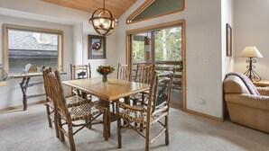 A dining area with a wooden table and chairs, a chandelier, and large windows. - Boulder Creek at Deer Valley Resort - Three Bedroom Condo with Hot Tub #1119 3 Condo (Park City)