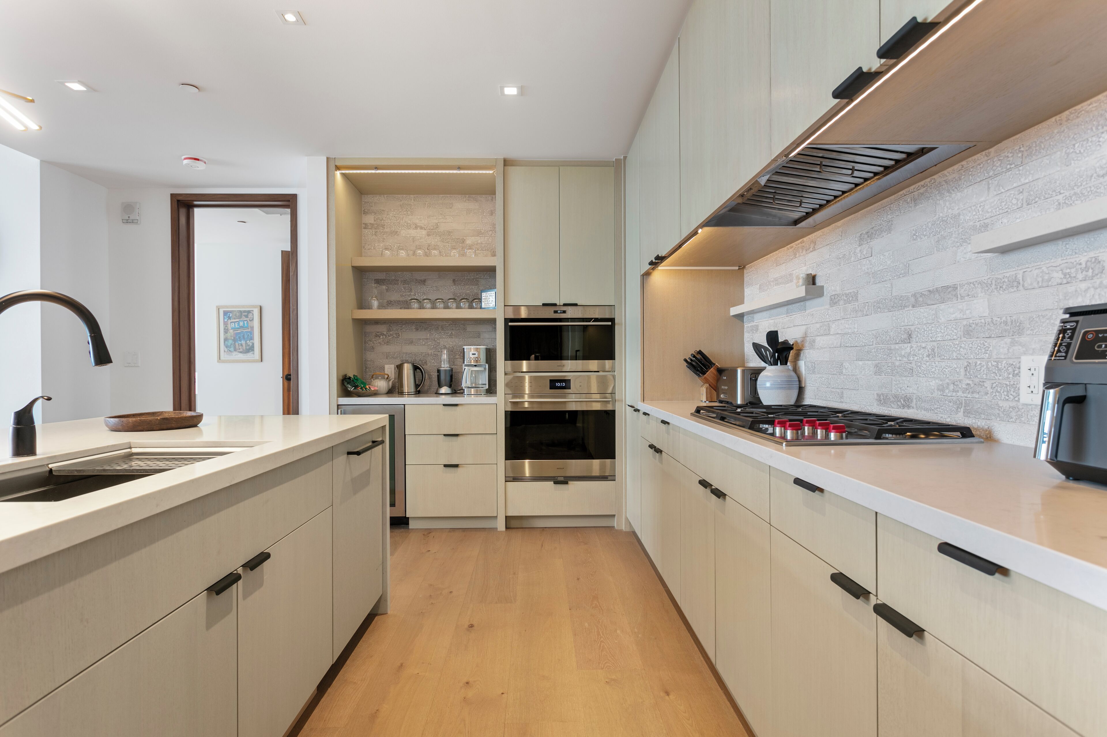 Una cocina moderna con armarios blancos, electrodomésticos de acero inoxidable y piso de madera.
