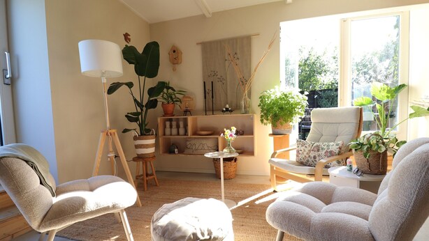 Un salon chaleureux avec un canapé, des fauteuils, une lampe et des plantes en pot.