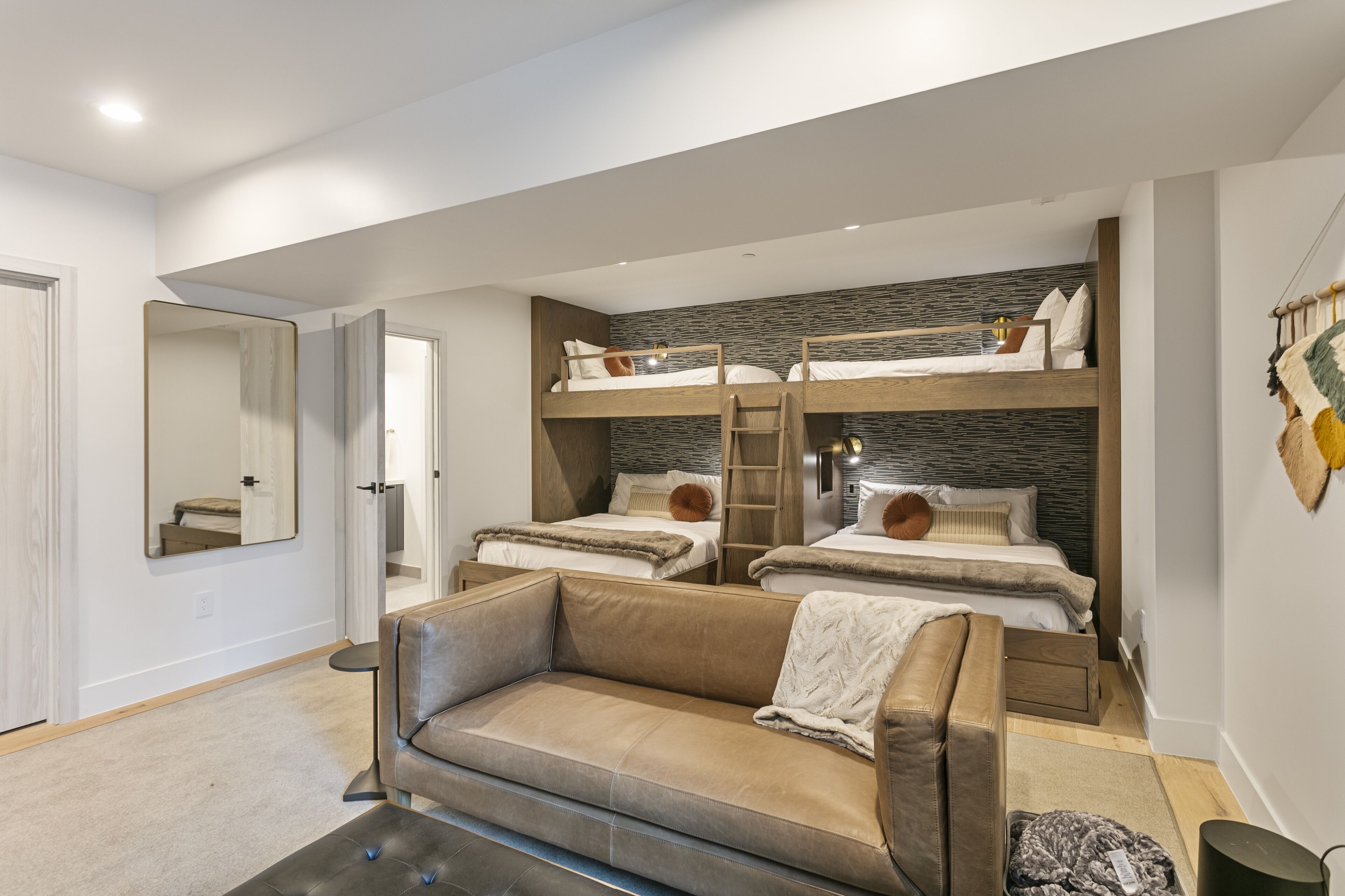 Un dormitorio moderno con literas, un sofá y un espejo.