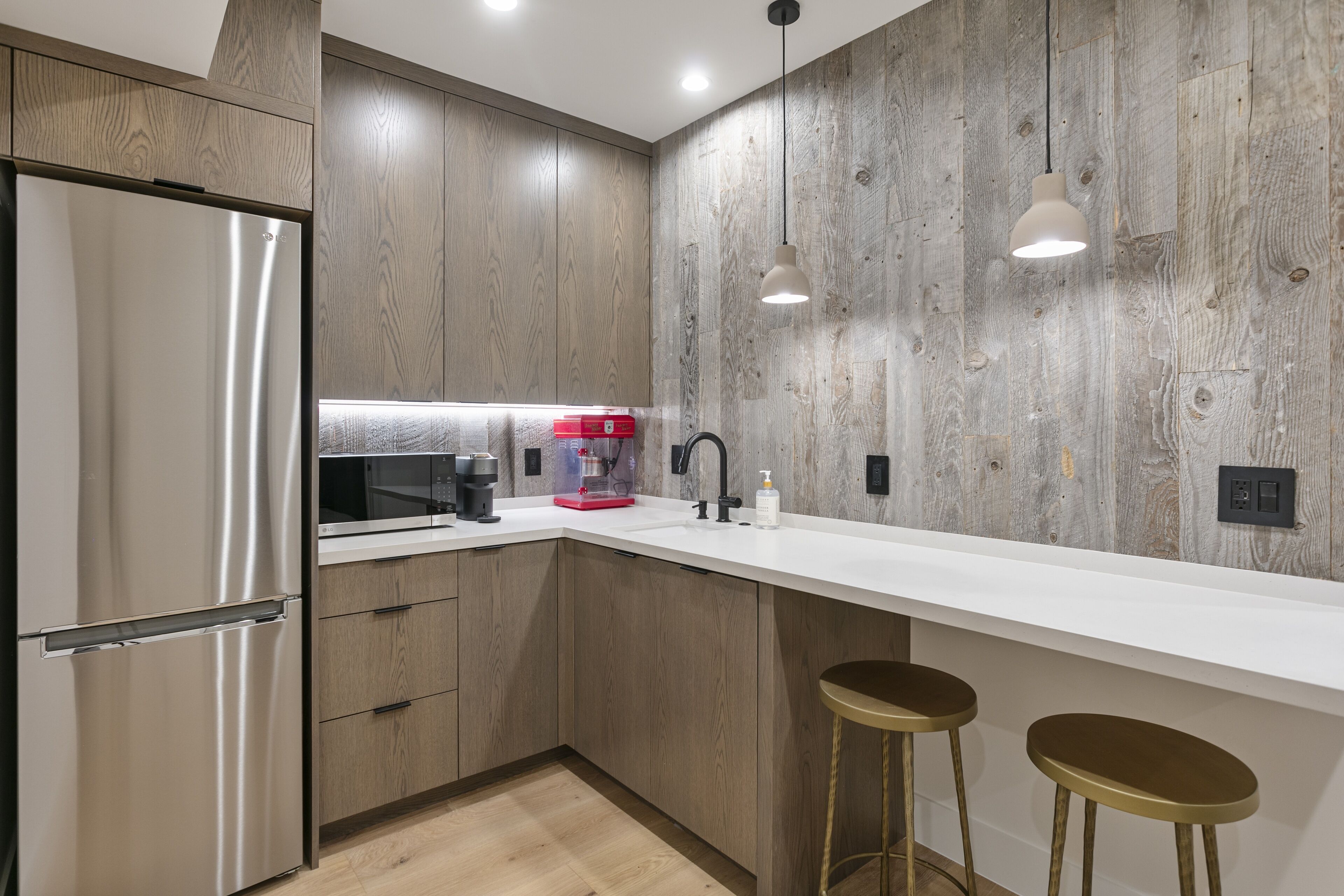 Eine moderne Küche mit Holzschränken, Edelstahlgeräten und einer weißen Arbeitsplatte.