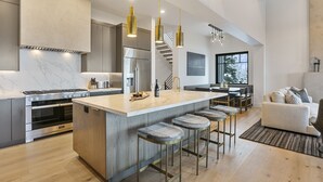 A modern kitchen with a central island, stainless steel appliances, and pendant lighting.