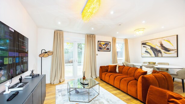 Una sala de estar moderna con un sofá modular, una mesa de centro de vidrio y un televisor de pantalla plana sobre un mueble.