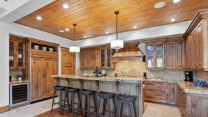 A spacious kitchen with wooden cabinets, a granite countertop, and a central island with bar stools. - Lookout at Deer Valley Resort - Four Bedroom Residence with Spa #6559 4 Condo (Park City)