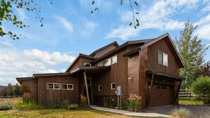 A modern two-story house with a wooden exterior, a garage, and a covered porch.