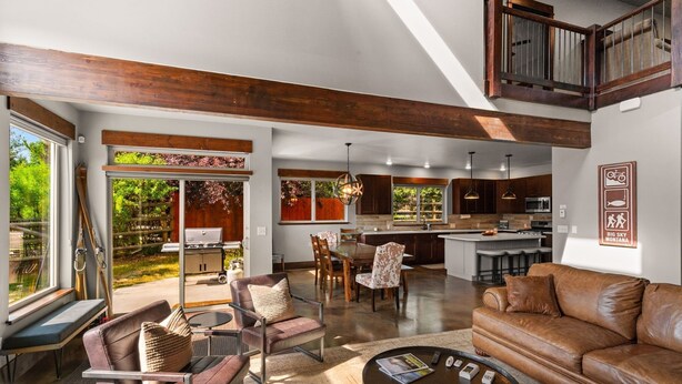 A spacious living area with a large window, a dining table, and a leather sofa.