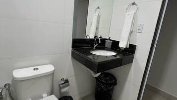 Un baño moderno con inodoro, lavamanos y espejo.