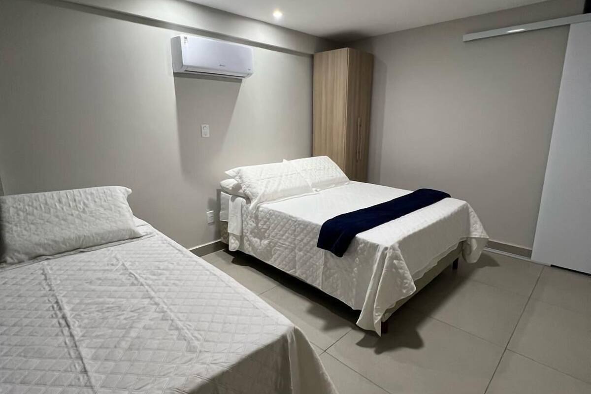 Ett hotellrum med två sängar, en garderob, en luftkonditioneringsanläggning och en taklampa.