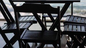 A table and chairs on a balcony with a view of the ocean. - Catamarã Pé da Areia (Angra dos Reis)