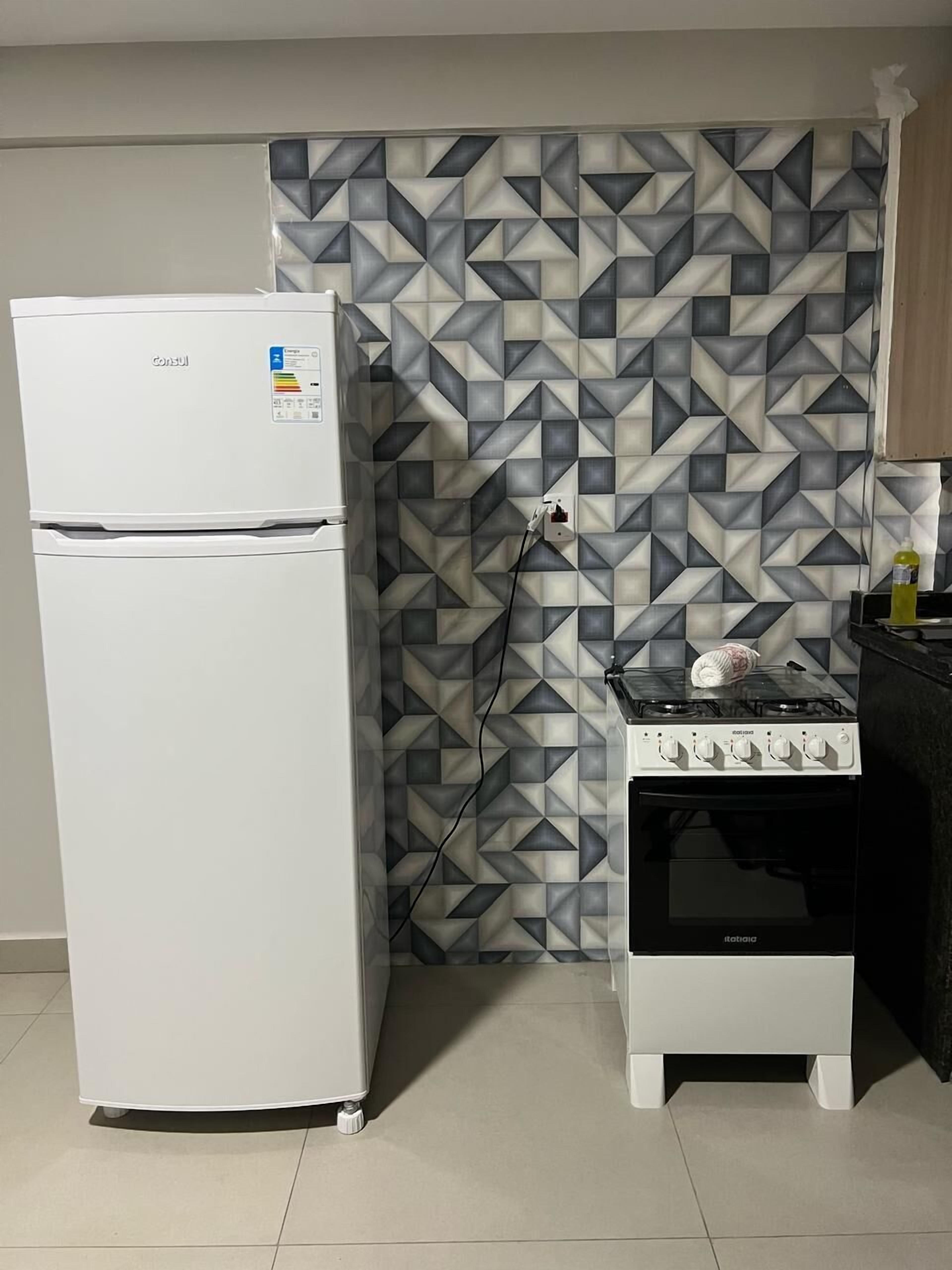 A kitchen with a white refrigerator, a gas stove, and a patterned wall.