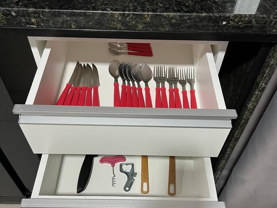 A drawer with utensils and a bottle opener.