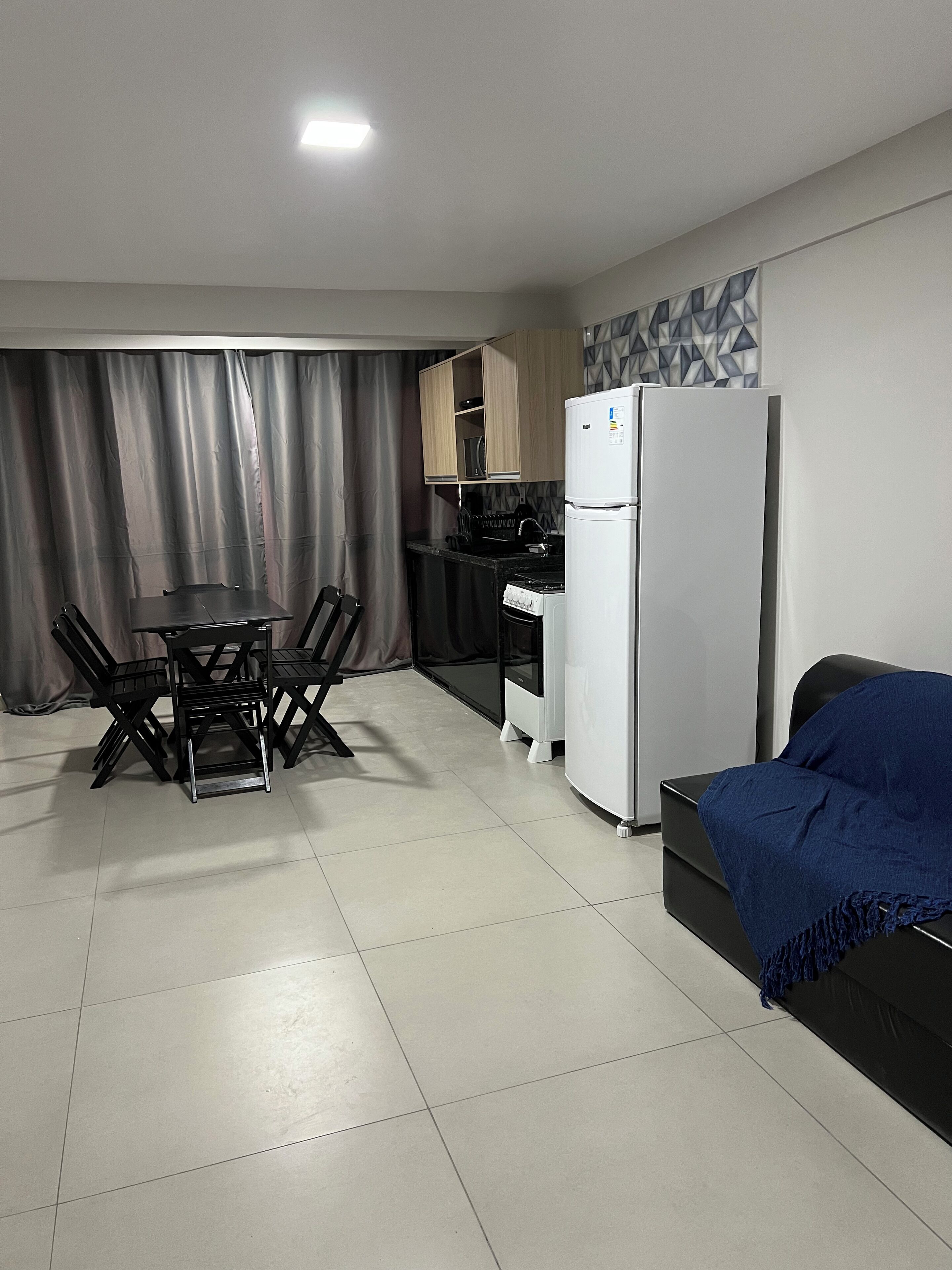 A compact living space with a dining area, kitchenette, and a bed.
