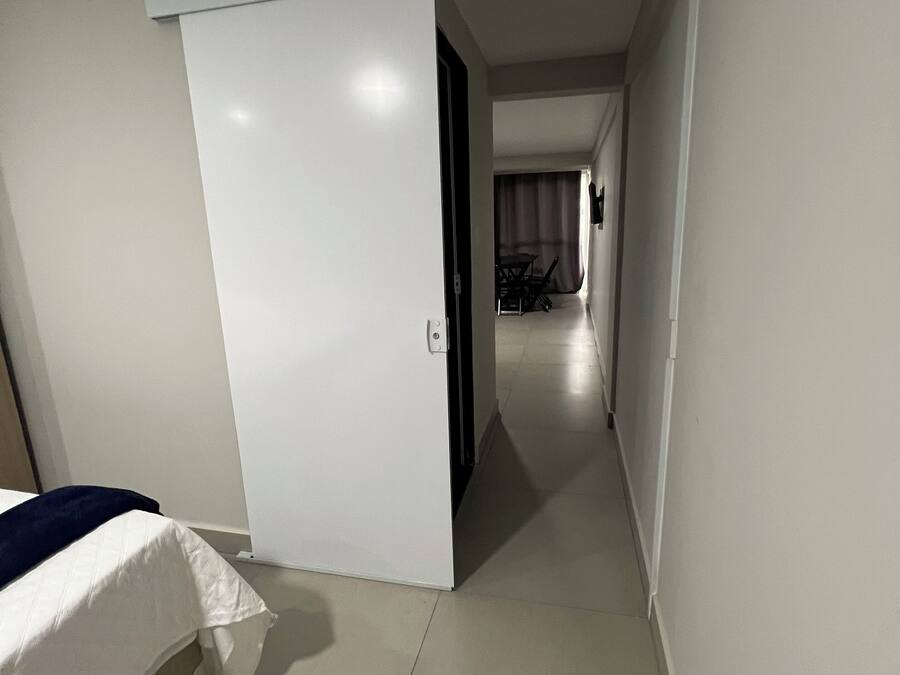 Een hotelkamer met een bed, een witte inbouwkast en een gang naar een eetgedeelte.