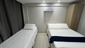 Una habitación de hotel con dos camas individuales, un armario, aire acondicionado y suelo de baldosas.