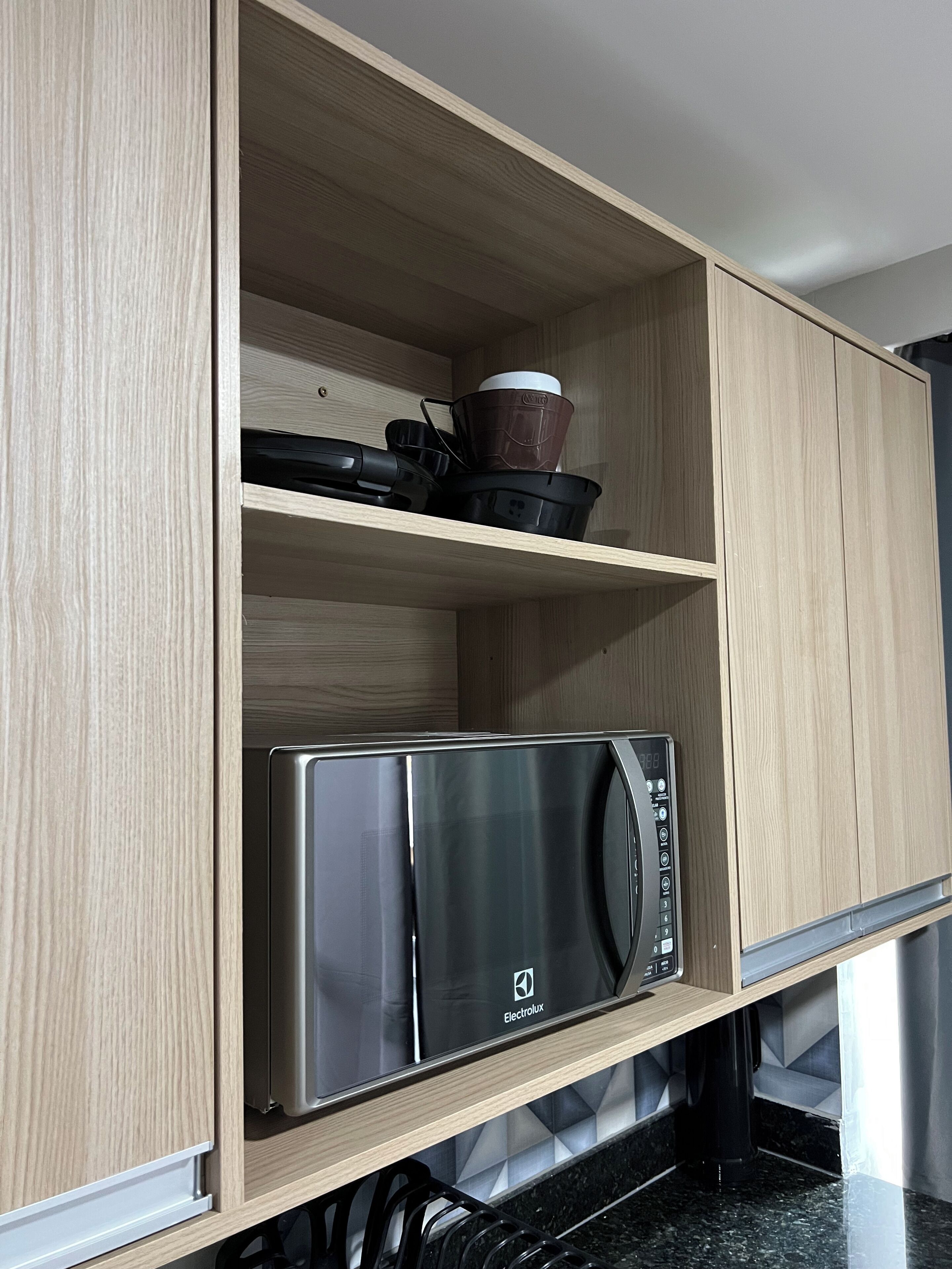 A kitchen with wooden cabinets, a microwave, and a coffee maker on the countertop.