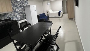 A compact kitchen with a dining table, chairs, a refrigerator, and a microwave. - Catamarã Pé da Areia (Angra dos Reis)
