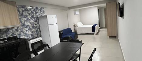 A compact kitchen with a dining table, chairs, a refrigerator, and a microwave.
