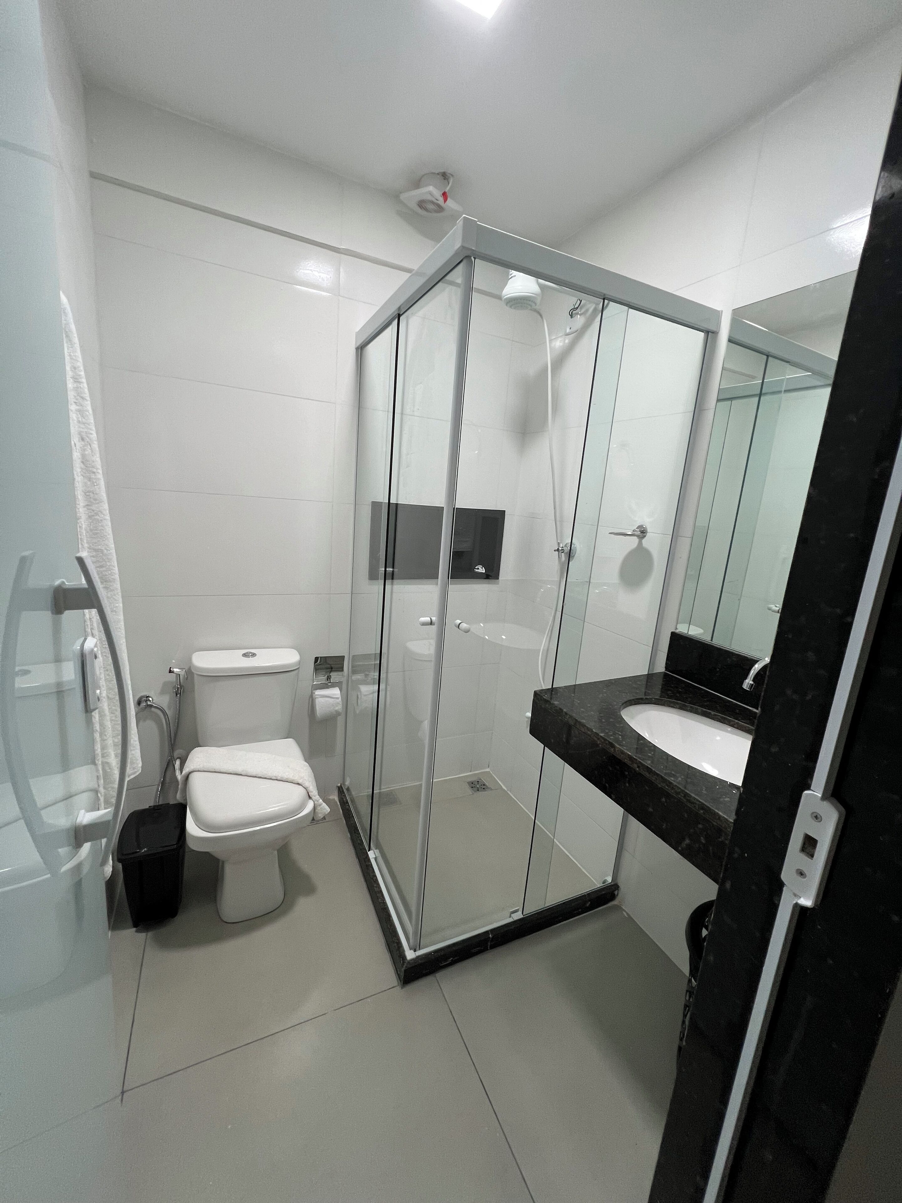A modern bathroom with a glass-enclosed shower, a white toilet, and a black countertop sink.