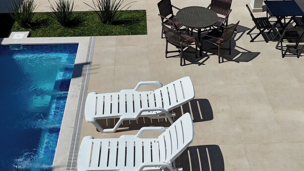 A pool area with lounge chairs, a table, and a view of the beach and ocean. - Catamarã Pé da Areia (Angra dos Reis)