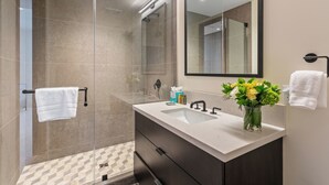 A modern bathroom with a glass shower enclosure, a sink with a vase of flowers, and a towel rack. - Argent At Deer Valley Resort - Hotel Room #105a Hotel Room (Park City)
