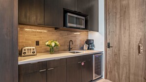 A modern kitchen with dark wooden cabinets, a stainless steel microwave, a toaster, and a coffee maker. - Argent At Deer Valley Resort - Hotel Room #105a Hotel Room (Park City)