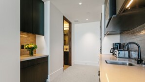 A modern kitchen with dark cabinetry, a light countertop, and a visible door leading to another room. - Argent At Deer Valley Resort - Hotel Room #105b Hotel Room (Park City)