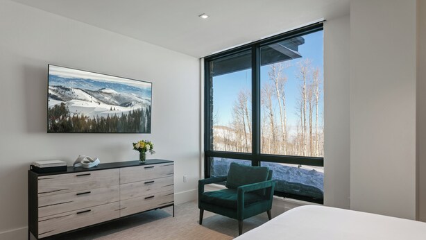 A bedroom with a large window, a bed, a dresser, and a painting of a snowy landscape. - Argent At Deer Valley Resort - Hotel Room #105b Hotel Room (Park City)