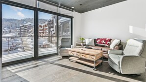 A modern living room with a large sliding glass door, a sofa, a coffee table, and a view of a snowy mountain area. - Argent at Deer Valley Resort - Two Bedroom Deluxe #401 2 Condo (Park City)