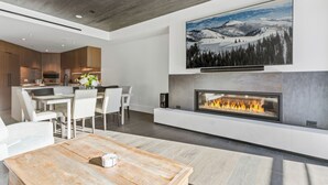A modern living room with a fireplace, a dining area, and a kitchen in the background. - Argent at Deer Valley Resort - Two Bedroom Deluxe #401 2 Condo (Park City)