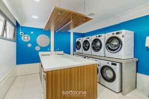 Un lavadero moderno con cuatro lavadoras, un mostrador de madera y una pared azul.