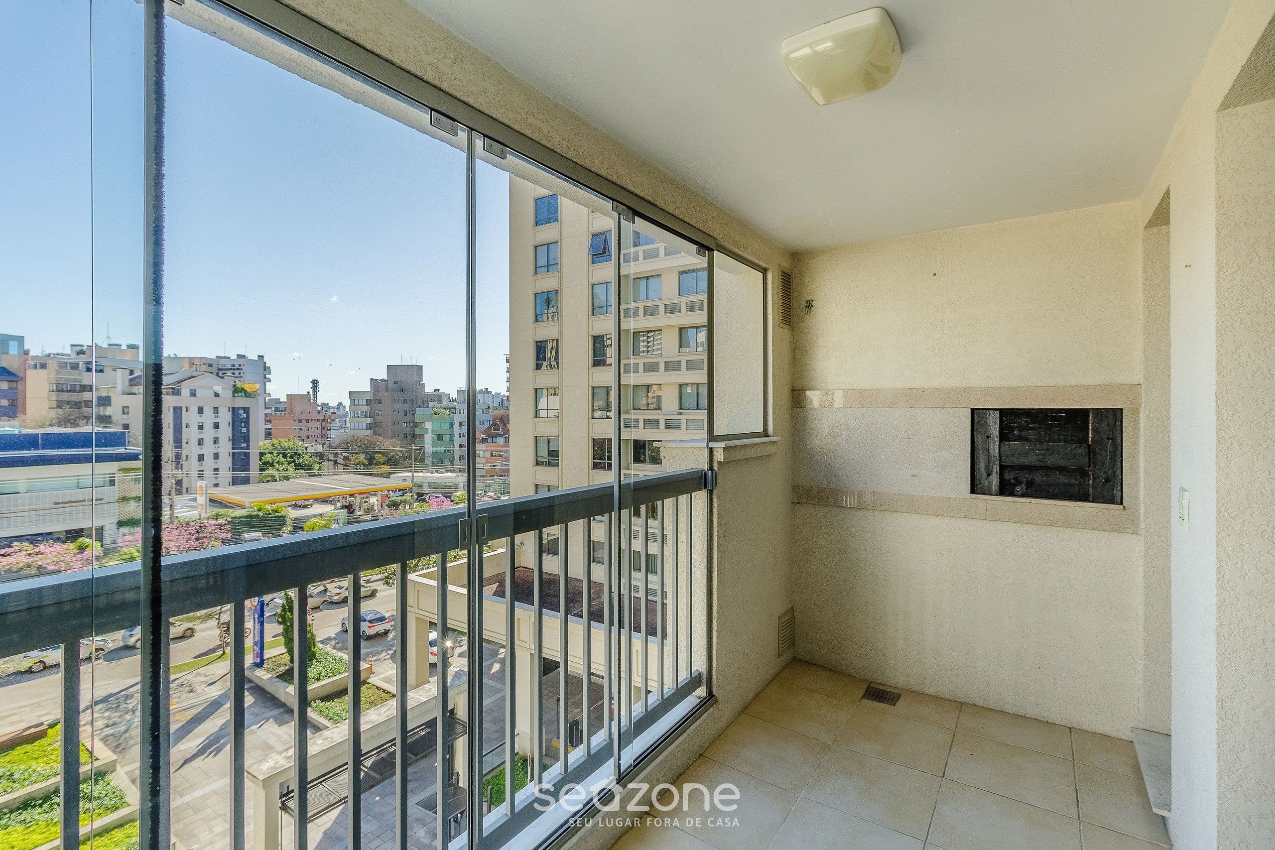 A balcony with a view of a cityscape, a small window, and a light fixture on the ceiling.