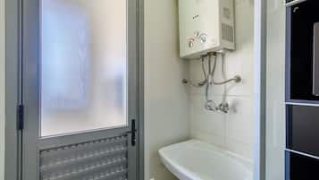 Casa de banho com lavatório branco, sanita e chuveiro.