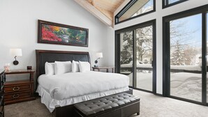 A bedroom with a large bed, a bench, a nightstand, a lamp, and a painting.
