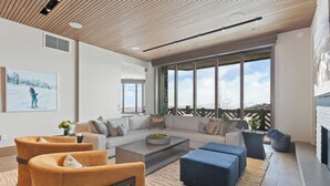 A modern living room with a large window, a fireplace, and a sofa.
