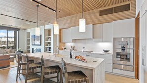 A modern kitchen with a large island, wooden ceiling, and stainless steel appliances.