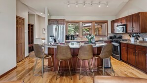 Una cocina moderna con armarios de madera, electrodomésticos de acero inoxidable y una isla central con taburetes de bar.