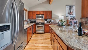 Una cocina moderna con electrodomésticos de acero inoxidable, armarios de madera y encimera de granito.