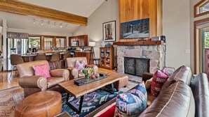 Un salón amplio con sofás de cuero, una mesa de centro y una chimenea de piedra.