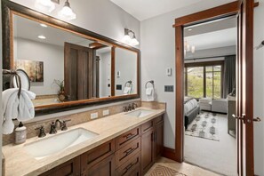 Ein Badezimmer mit zwei Waschbecken, einem großen Spiegel und Holzschränken.