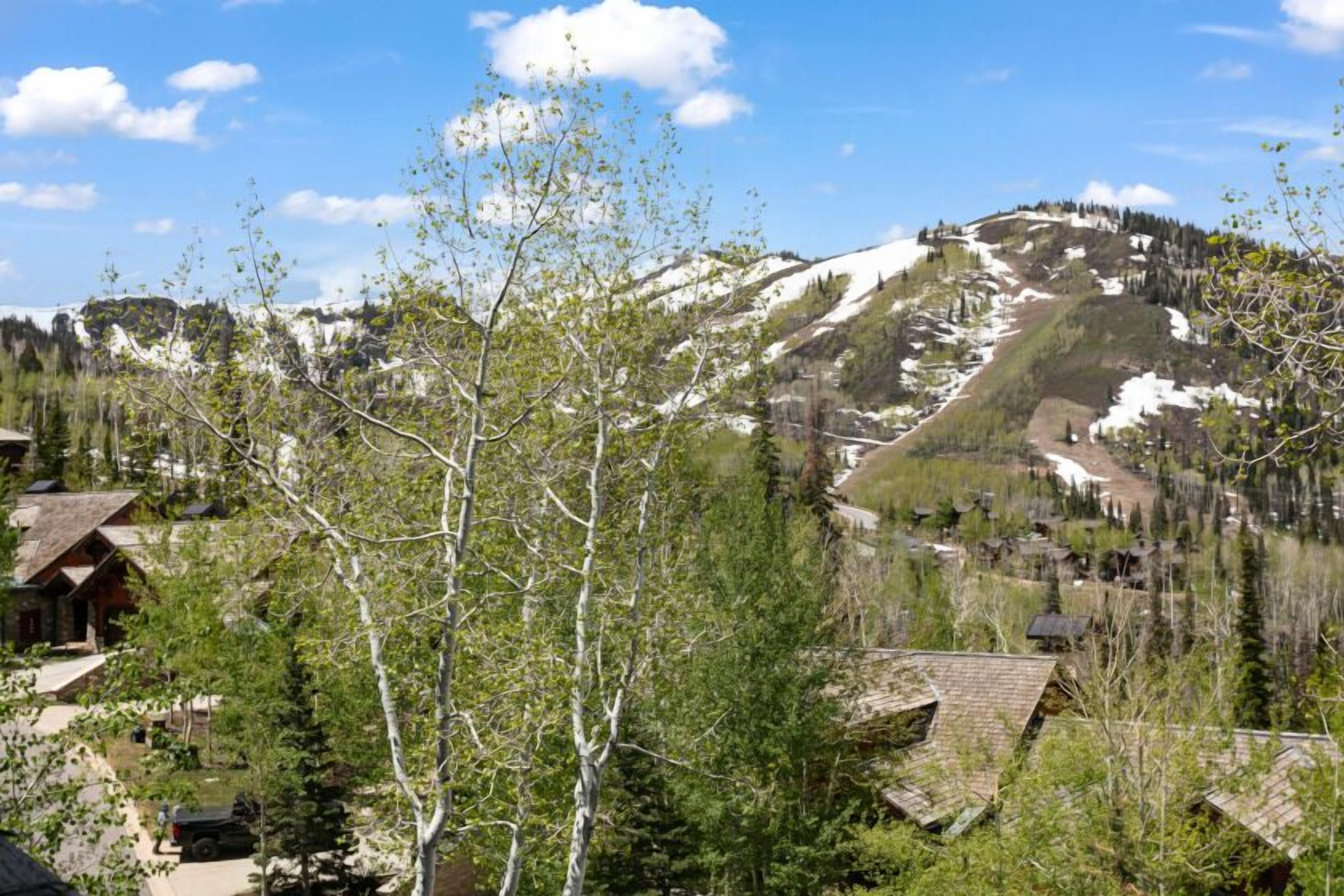 Un pueblo de montaña con casas tradicionales de madera, una pista de esquí y cielo despejado.