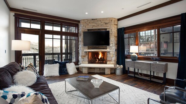 A living room with a stone fireplace, a flat-screen TV, a sofa with decorative pillows, and a coffee table. - Arrowleaf Lodge - Two Bedroom Condo Residence #209 by Deer Valley Resort (Park City)
