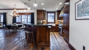 A modern kitchen with a central island, bar stools, wooden cabinets, and a chandelier. - Arrowleaf Lodge - Two Bedroom Condo Residence #209 by Deer Valley Resort (Park City)
