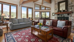 A spacious living room with a fireplace, large windows offering a mountain view, and a cozy seating area.
