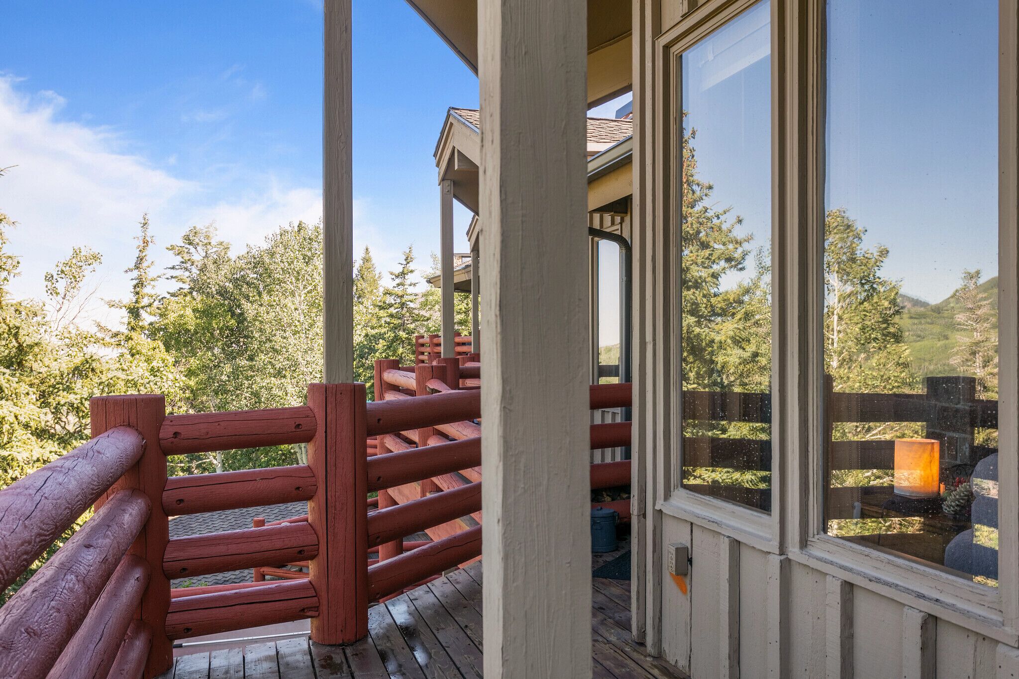 A wooden deck with a red railing overlooking a mountainous landscape.