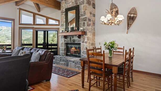 A cozy living room with a stone fireplace, wooden dining table, and comfortable seating.