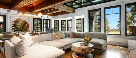 A spacious living room with a large sectional sofa, a round coffee table, and a wooden ceiling.