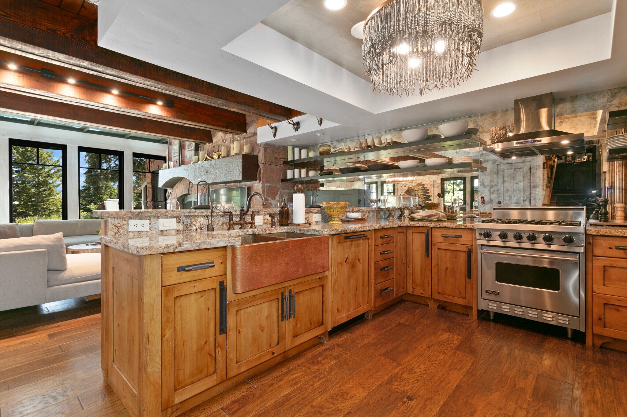 Una cocina amplia con armarios de madera, una isla grande, electrodomésticos de acero inoxidable y un candelabro.