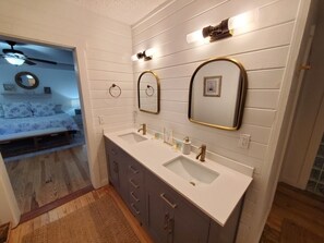 Une salle de bain avec un double lavabo, un meuble-lavabo et deux miroirs fixés au mur.